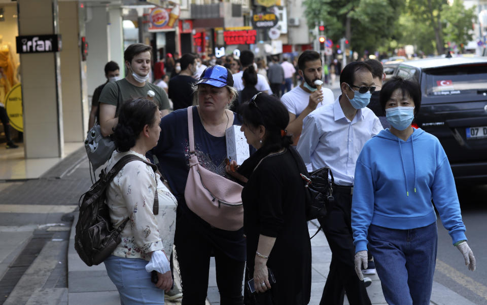 People, some wearing face masks to protect against the coronavirus, walk along a popular street, in Ankara, Turkey, Sunday, June 14, 2020. Turkey's President Recep Tayyip Erdogan has revealed Tuesday new plans to ease restrictions in place to curb the spread of the coronavirus, including the July 1 reopening of theaters, cinemas and other entertainment centers. (AP Photo/Burhan Ozbilici)