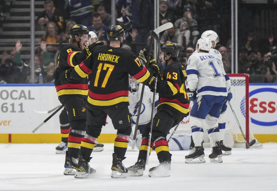 Vancouver Canucks' Brock Boeser (6), Filip Hronek (17) and Quinn Hughes (43) celebrate Boeser's goal against the Tampa Bay Lightning during the second period of an NHL hockey game in Vancouver, B.C., on Tuesday, Dec. 12, 2023. (Darryl Dyck/The Canadian Press via AP)