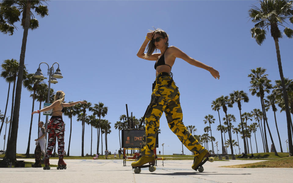 FILE - In this May 13 2020 file photo, a skater who goes by the name Kels, right, and Tricia Plinzke practice at Venice Beach during the coronavirus outbreak in Los Angeles. In state after state, the local health departments charged with doing the detective work of running down the contacts of coronavirus patients are falling well short of the number of people needed to do the job. (AP Photo/Mark J. Terrill, File)