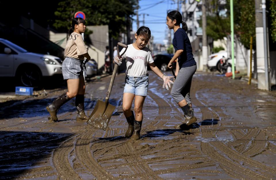 Children clear mud from a street after floodwaters receded in the aftermath of Typhoon Hagibis, in Kawasaki on Oct. 13, 2019. (Photo: William West/AFP via Getty Images)