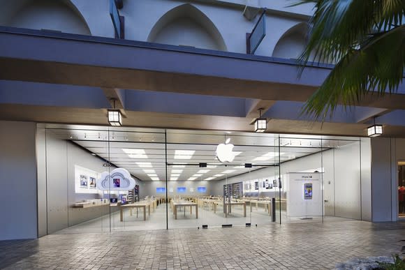 Apple Store with glass front windows and logo atop the doorway, with machines inside.