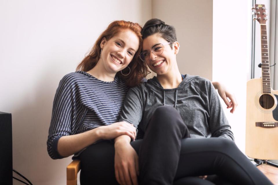 A happy couple shares a chair in a sunny room