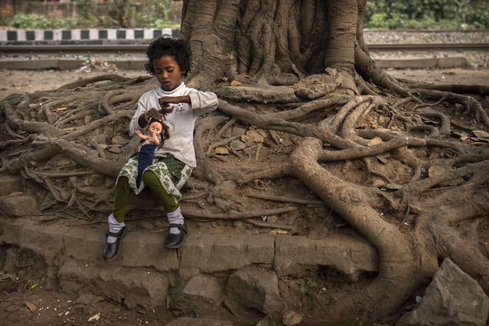 A girl child plays with a doll sitting under a tree at a roadside, in Guwahati, in Indian northeastern state of Assam, Friday, Feb. 10, 2023. In India, the legal marriageable age is 21 for men and 18 for women. Poverty, lack of education, and social norms and practices, particularly in rural areas, are considered reasons for child marriages across the country. UNICEF estimates that at least 1.5 million girls under 18 get married in India every year, making it home to the largest number of child brides in the world, accounting for a third of the global total. (AP Photo/Anupam Nath)