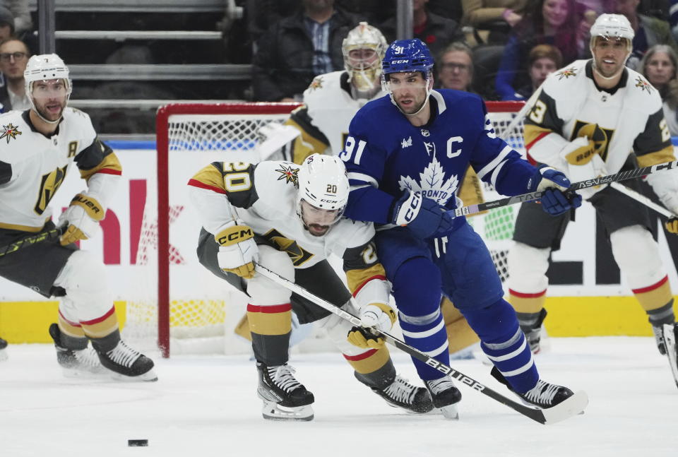 Toronto Maple Leafs forward John Tavares (91) and Vegas Golden Knights forward Chandler Stephenson (20) battle for the puck during the first period of an NHL hockey game, Tuesday, Nov. 8, 2022 in Toronto. (Nathan Denette/The Canadian Press via AP)