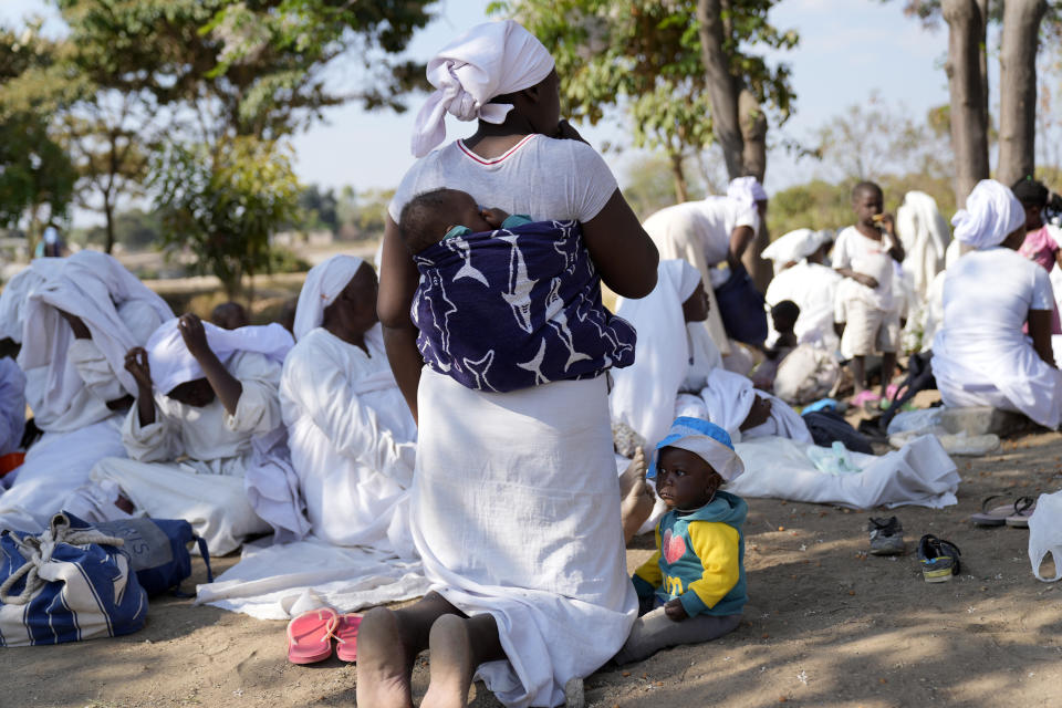 A woman member of the apostolic church kneels while praying in a bushy area in the impoverished Epworth region outside Harare, Friday, Sept. 16, 2022. Church members in Zimbabwe are getting their children vaccinated against measles in secret amid a deadly outbreak. It's to avoid being shunned by religious leaders who are opposed to modern medicine. (AP Photo/Tsvangirayi Mukwazhi)