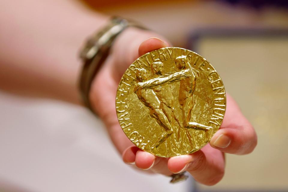 A worker holds Russian journalist Dmitry Muratov's 23-karat gold medal of the 2021 Nobel Peace Prize before being auctioned at the Times Center, Monday, June 20, 2022, in New York. (AP Photo/Eduardo Munoz Alvarez) ORG XMIT: NYE302