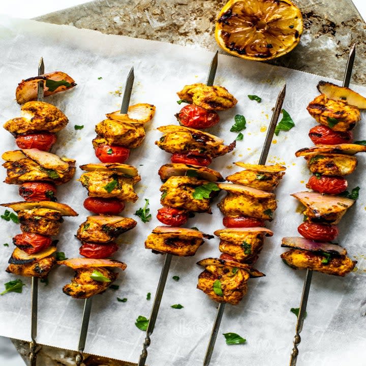 Five chicken skewers with tomatoes.