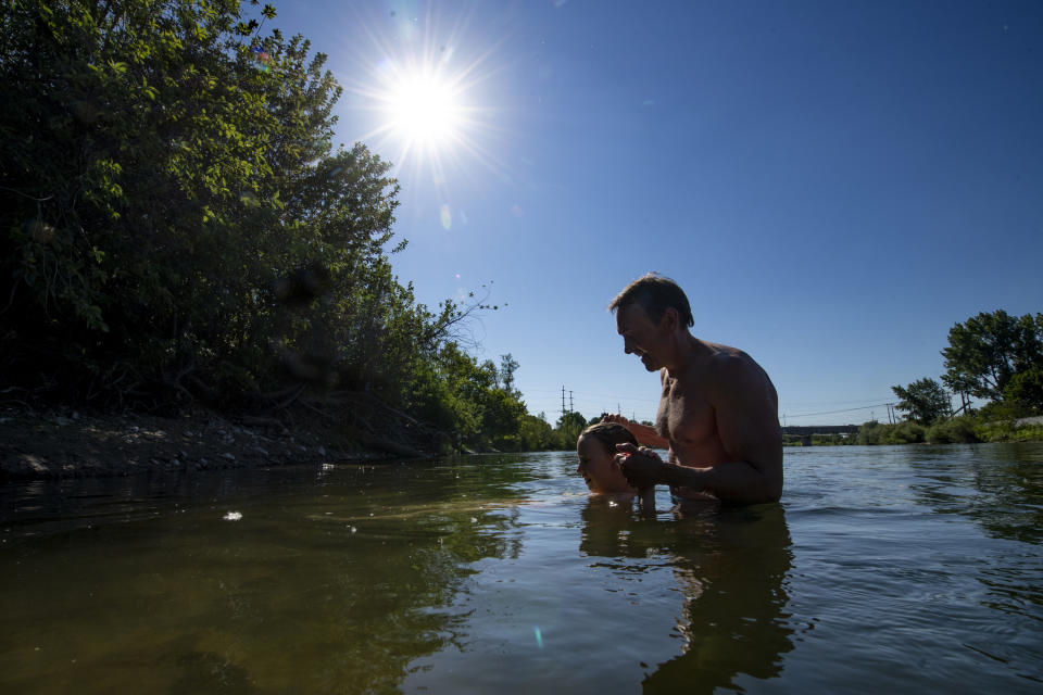 Jeff Krupczak and daughter Savanna, 12, cool off in the Clark Fork River in Missoula, Montana, on Wednesday, June 30, 2021. (AP Photo/Tommy Martino)