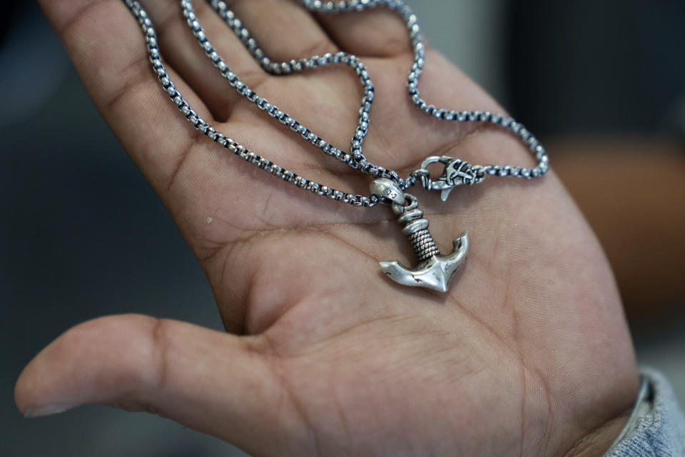 Jhonatan Gelvez, 21, of Colombia, holds a necklace given to him by his fianceé at a makeshift shelter for migrants at O'Hare International Airport, Wednesday, Sept. 20, 2023, in Chicago. Fleeing violence in his home country, Gelvez and his fianceé were separated when detained at the border. He awaits her release and their reunification. (AP Photo/Erin Hooley)