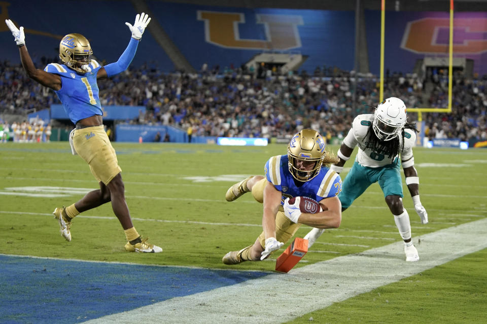 UCLA running back Carson Steele, center, scores as wide receiver J. Michael Sturdivant, left, celebrates and Coastal Carolina cornerback Juan Powell defends during the first half of an NCAA college football game Saturday, Sept. 2, 2023, in Pasadena, Calif. (AP Photo/Mark J. Terrill)