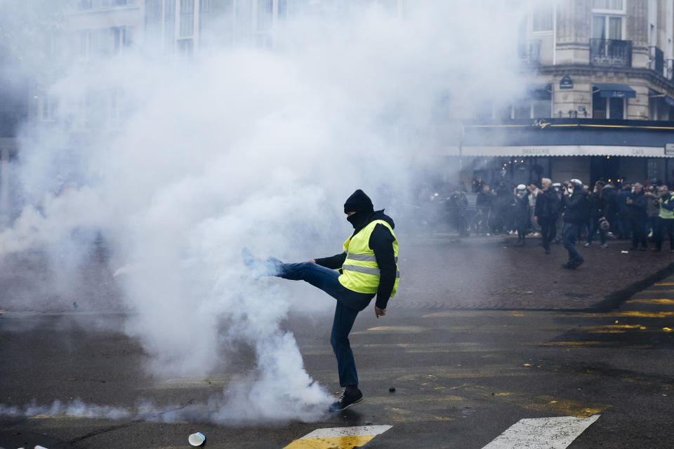 A protestor kicks away a tear gas canister during a yellow vest demonstration marking the first anniversary in Paris, Saturday, Nov. 16, 2019. Paris police fired tear gas to push back yellow vest protesters trying to revive their movement on the first anniversary of the sometimes violent uprising against President Emmanuel Macron and government economic policies (AP Photo/Kamil Zihnioglu)