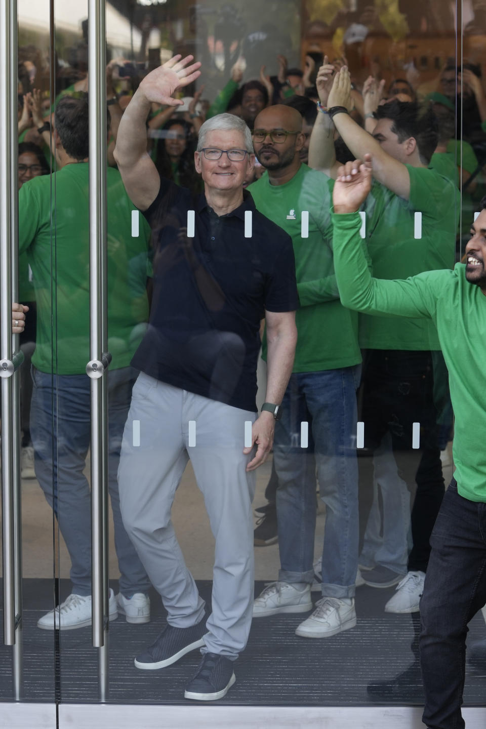 Apple CEO Tim Cook waves to the dozens of people waiting outside during the opening of the first Apple Inc. flagship store in Mumbai, India, Tuesday, April 18, 2023. Apple Inc. opened its first flagship store in India in a much-anticipated launch Tuesday that highlights the company’s growing aspirations to expand in the country it also hopes to turn into a potential manufacturing hub. (AP Photo/Rafiq Maqbool)