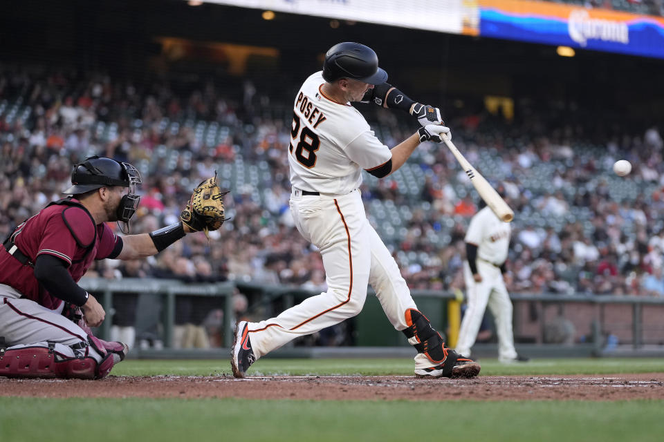 San Francisco Giants' Buster Posey hits a three-run home run in front of Arizona Diamondbacks catcher Stephen Vogt during the first inning of a baseball game Wednesday, June 16, 2021, in San Francisco. (AP Photo/Tony Avelar)