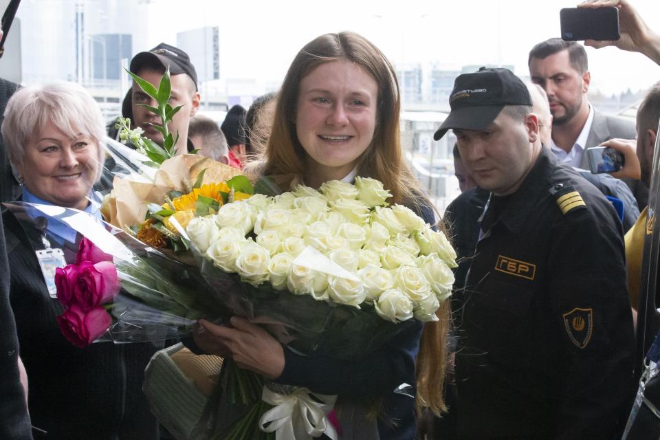 Russian agent Maria Butina, center, holds a bunch of flowers upon her arrival from the United States at Moscow International Airport Sheremetyevo outside Moscow Moscow, Russia, Saturday, Oct. 26, 2019. Butina, a gun rights activist who sought to infiltrate conservative U.S. political groups and promote Russia's agenda around the time that Donald Trump rose to power, was released Friday from a low-security facility in Florida. (AP Photo/Alexander Zemlianichenko)