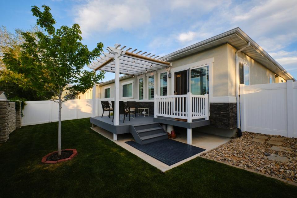 Tan home with small pergola and deck. 