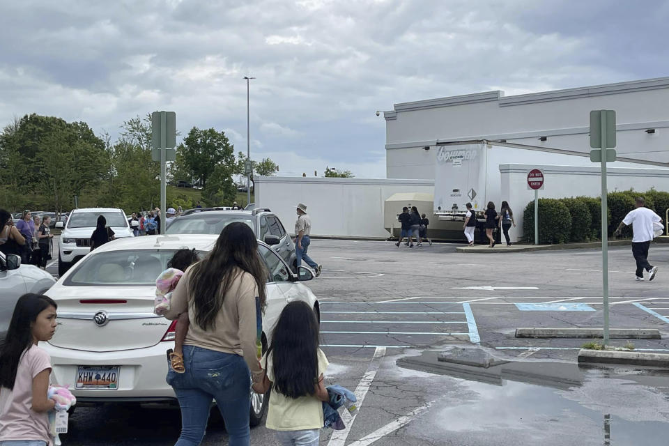 People walk through a parking lot at the Columbiana Centre mall in Columbia, S.C. on Saturday, April 16, 2022, as police investigate a shooting at the shopping center. (Justin Smith via AP)