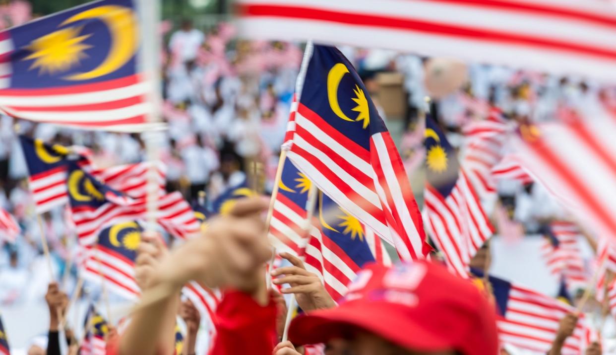 Citizens holding up miniature Malaysia flags during a rally. 