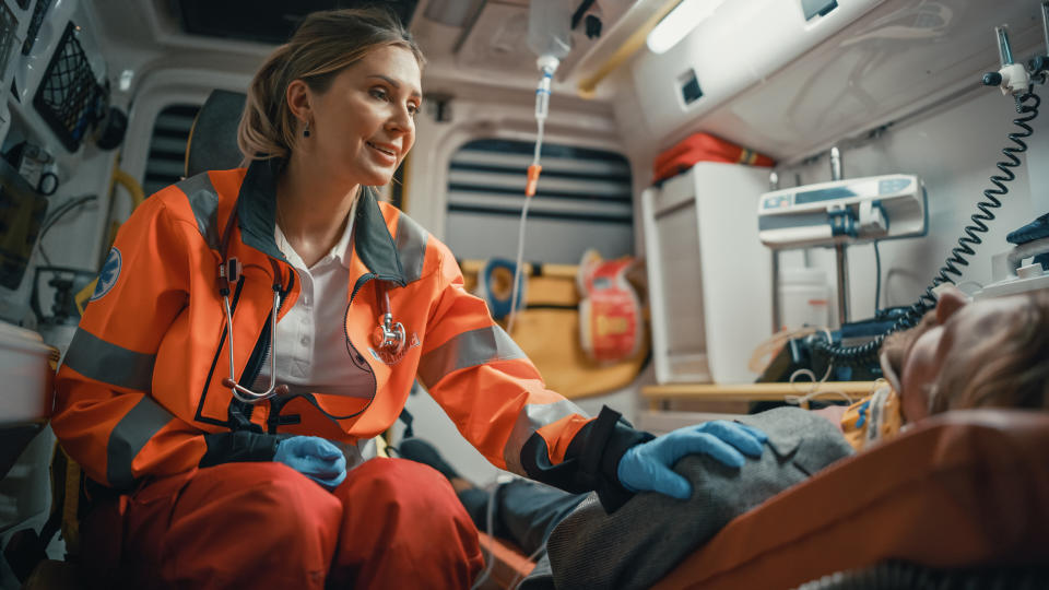 A paramedic in an ambulance attends to a patient lying on a stretcher, providing care and comfort