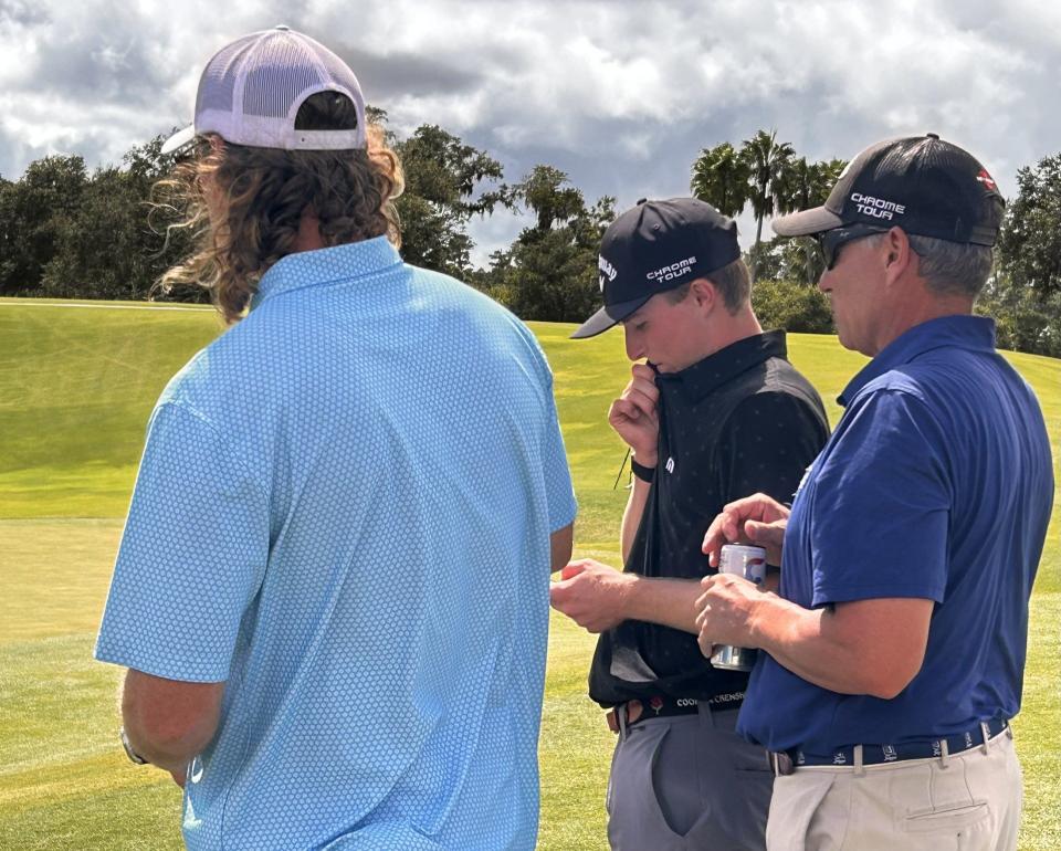 Blades Brown (center) waits by the 18th green of the Players Stadium Course at TPC Sawgrass on Sept. 1 between his caddie Jack Bethmann (left) and his father Tony Brown while Hamilton Coleman putts out. Brown and Coleman went to a playoff in the Junior Players Championship before Coleman won on the second hole.