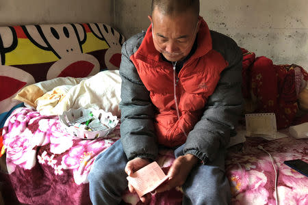 Wang Zhaohong, who suffers from silicosis, holds his bankbook as he reviews the debt he owes, on his bed in Sangzhi county, Hunan province, China November 27, 2018. Picture taken November 27, 2018. REUTERS/Sue-Lin Wong