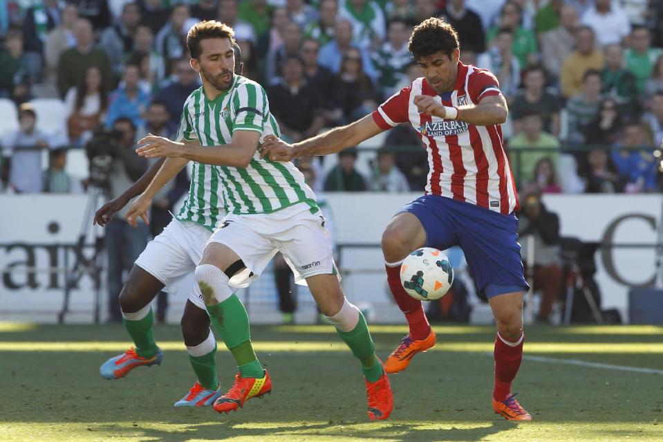 Atletico de Madrid's Diego Costa, right, and Betis' Jordi Figueras , left, vie for the ball during their La Liga soccer match at the Benito Villamarin stadium, in Seville, Spain on Sunday, March 23, 2014. (AP Photo/Angel Fernandez)
