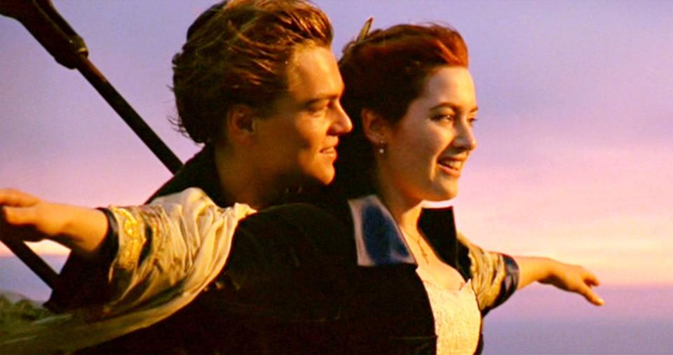 leonardo dicaprio holding kate winslet, who has her arms expanded outward, on the front of a ship in a promotional still for the movie titanic
