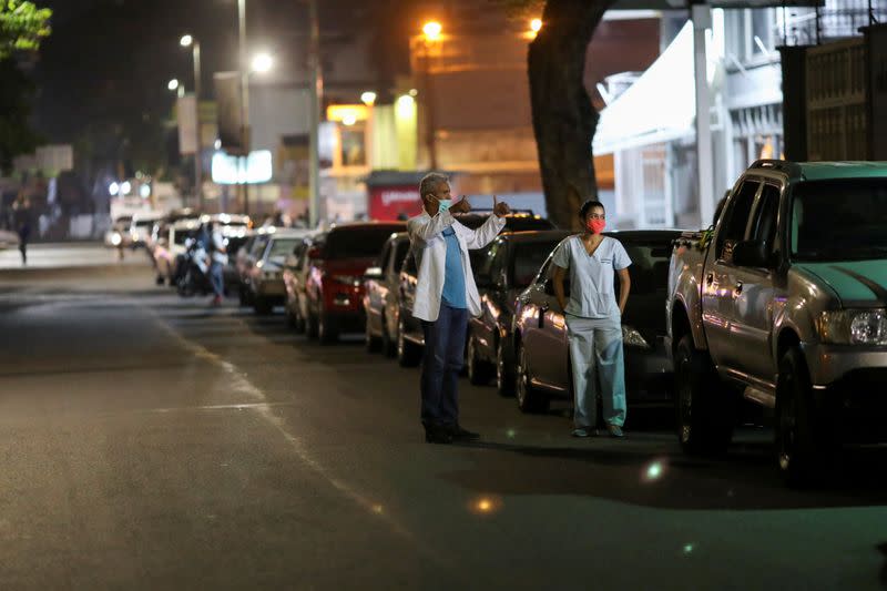 FILE PHOTO: Doctors Carlos Martinez and Maria Martinez wait in line to get fuel at a gas station, during a nationwide quarantine due to the coronavirus disease (COVID-19) outbreak, in Caracas