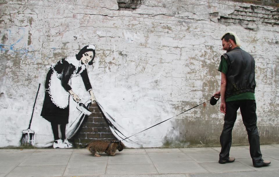 LONDON - MAY 16:  Graffitti art by the 'guerilla' artist Banksy is seen on May 16, 2006 in Chalk Farm, London. The striking large scale spray-painted image entitled 'Sweeping It Under The Carpet' depicts a maid who cleaned the artist's room in a motel in Los Angeles. The piece commissioned by 'The Independent' newspaper edited on Tuesday by U2's frontman Bono, is intended to represent a metaphor for the west's reluctance to tackle issues such as Aids in Africa.  (Photo by Dave Etheridge-Barnes/Getty Images)