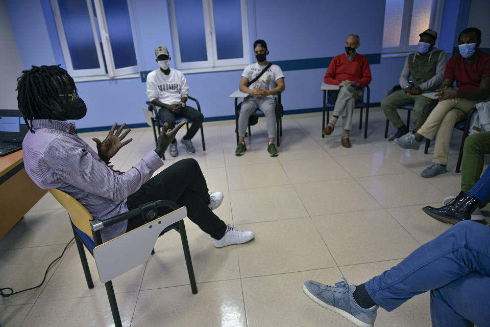 Mbaye Bbacar Diouf, left, talks with migrants and volunteers during a workshop supporting migrants, in Bilbao, northern Spain, Wednesday, Nov. 18, 2020. Mbaye Babacar Diouf's life as a migrant in Europe took a turn for the better when he was adopted in Spain at the age of 28. That enabled him to pay his debts to human traffickers, study nursing and find a job at a Spanish hospital. Now he's giving back to the community. In a Bilbao hospital he cares for COVID-19 patients. (AP Photo/Alvaro Barrientos)