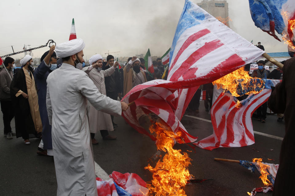 Clerics burn representations of the U.S. flag during the annual rally commemorating the anniversary of Iran's 1979 Islamic Revolution in Tehran, Iran, Friday, Feb. 11, 2022. Thousands of cars and motorbikes paraded in the celebration, although fewer pedestrians were out for a second straight year due to concerns over the coronavirus pandemic. (AP Photo/Vahid Salemi)