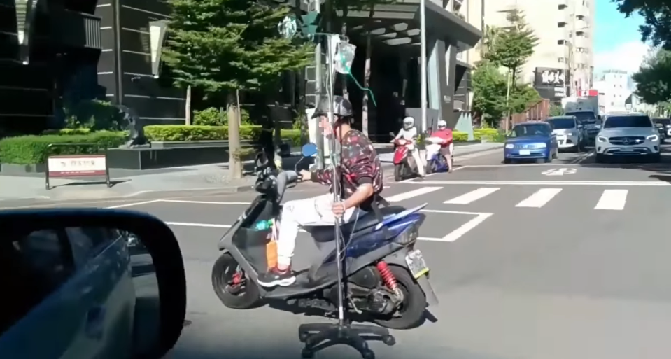 騎士抓著點滴架單手騎車。（圖／翻攝自爆廢公社） 