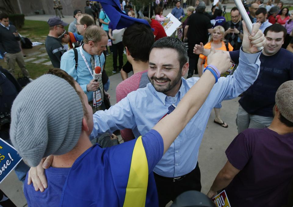 Gay rights supporters David Martinez, right, hugs Christopher Heinl, after they learn Arizona Gov. Jan Brewer has vetoed SB1062, a bill designed to give added protection from lawsuits to people who assert their religious beliefs in refusing service to gays, at the Arizona Capitol on Wednesday, Feb. 26, 2014, in Phoenix. (AP Photo/Ross D. Franklin)