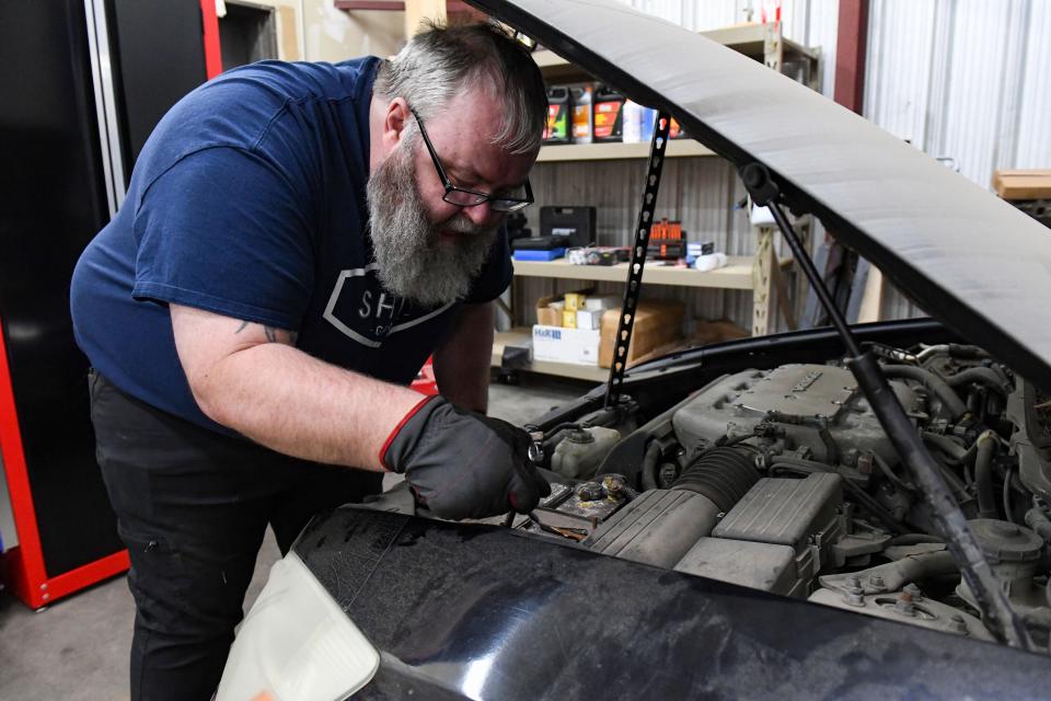 SHIFT Garage volunteer Greg Matson cleans under the hood of a donated car on Wednesday, January 12, 2022, in Sioux Falls.