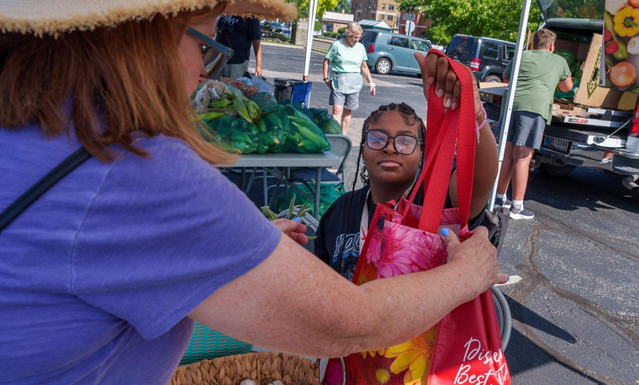 Mother Love's Garden camper Aeriana Grigsby, 14, sells camp vegetables Thursday, Aug. 3, 2023, at the North Church Farmers Market along 38th Street in Indianapolis.