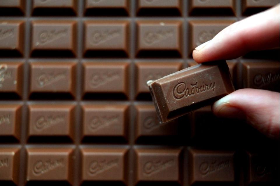 Fingers hold single block of Cadbury Dairy Milk chocolate