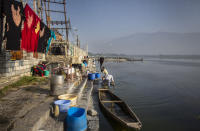 A Kashmiri washerman washes clothes on the banks of Dal lake in Srinagar, Indian controlled Kashmir, Tuesday, Sept. 14, 2021. Weeds, silt and untreated sewage are increasingly choking the sprawling scenic lake, which dominates the city and draws tens of thousands of tourists each year. (AP Photo/Mukhtar Khan)