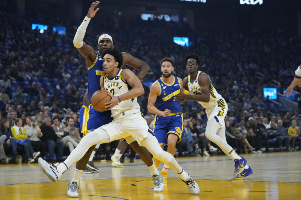 Indiana Pacers guard Andrew Nembhard drives to the basket while defended by Golden State Warriors center Kevon Looney during the first half of an NBA basketball game in San Francisco, Monday, Dec. 5, 2022. (AP Photo/Godofredo A. Vásquez)