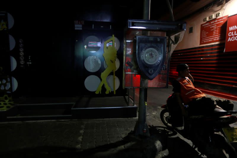 Motorbike driver waits for clients in front of closed bars in Pattaya