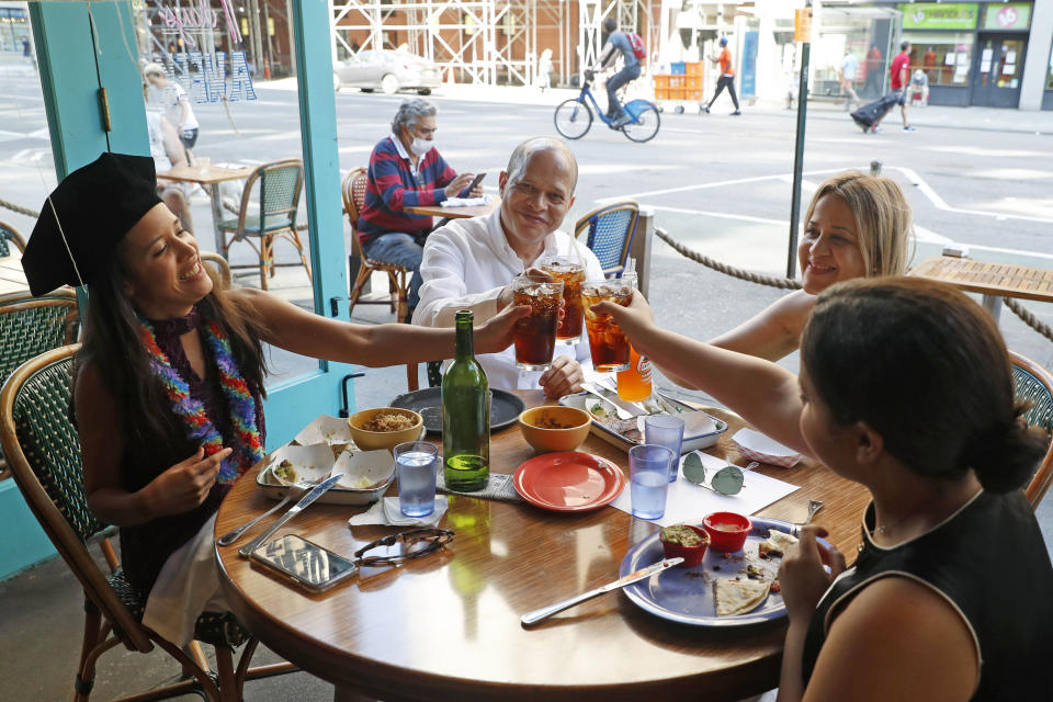 A graduate toasts with her family at a restaurant on Manhattan's Upper West Side on July 20, 2020. (AP Photo/Kathy Willens, File)