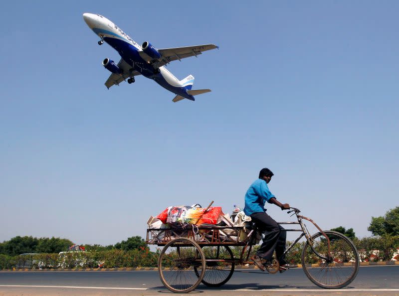 An IndiGo Airlines aircraft prepares to land as a man paddles his cycle rickshaw in Ahmedabad