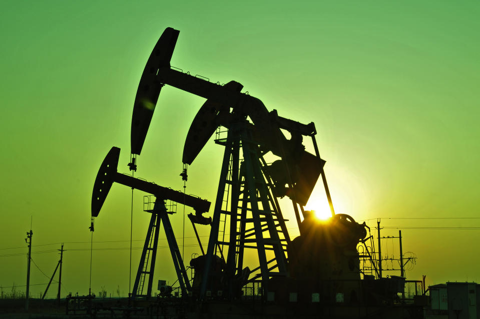 A silhouette of pumpjacks in a field.