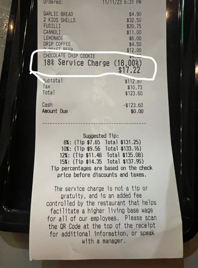 restaurant bill with an added 18% service charge and a note that this charge is not a tip and guidelines on how much to tip on top of the charge