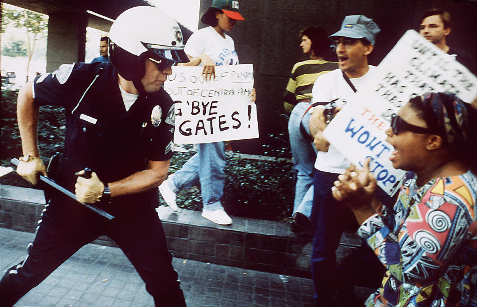 Police officer using baton on protester