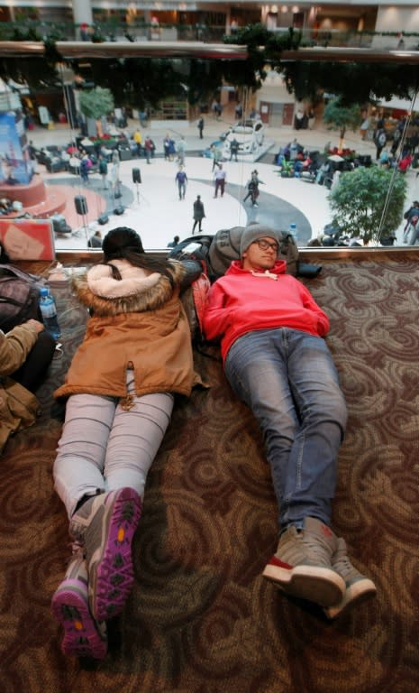 Two foreign exchange students rest at Atlanta airport as they wait for a flight the day after a power outage shut down the facility