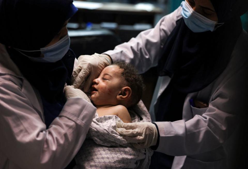 The baby boy, named as Omar, in the arms of two nurses wearing face masks.