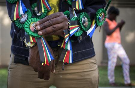 A man sells pins with the image of Nelson Mandela outside the Mandela house in the Houghton Estates neighborhood of Johannesburg, South Africa December 7, 2013. REUTERS/Adrees Latif