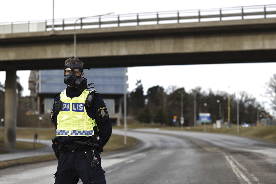 A police officer with a gas mask stands guard near the Security Police's headquarters in Solna, north of Stockholm, Sweden, Friday Feb. 23, 2024. A suspected gas leak at the headquarters of Sweden’s security agency on Friday forced the authorities to evacuate some 500 people from the facility, Swedish broadcaster TV4 said. (Fredrik Persson/TT News Agency via AP)