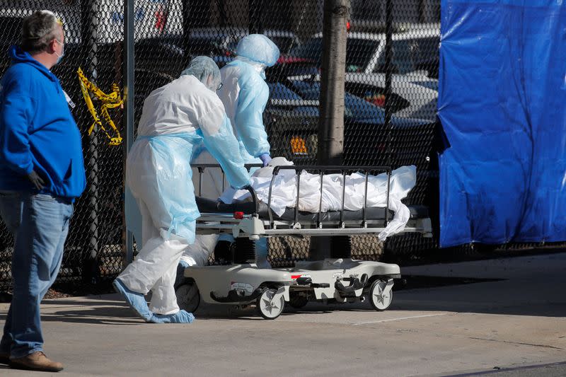 Healthcare workers wheel bodY of deceased person to morgue outside Wyckoff Heights Medical Center during outbreak of coronavirus disease (COVID-19) in New York