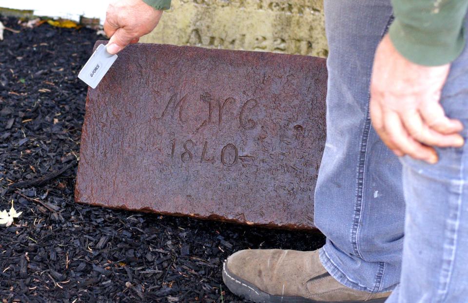 Peter Maneri, President of the Holmdel Historical Society, brushes the corner stone from the first residence on Potter's Farm.