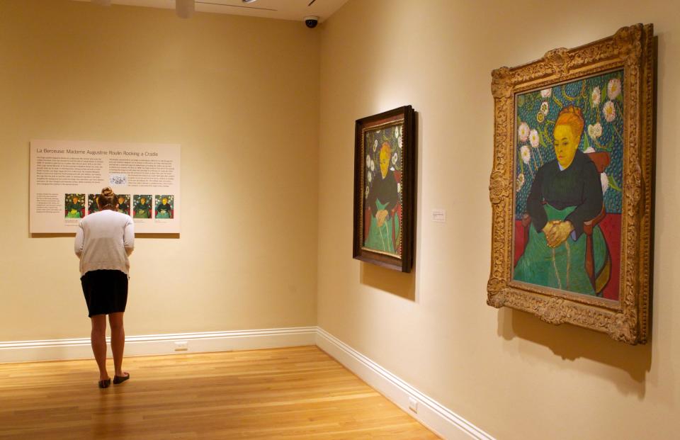 In this Oct. 8, 2013 photo, a woman reads about Vincent van Gogh's repetition of "Madame Roulin Rocking the Cradle," right, on display at The Phillips Collection in Washington. In the midst of the shutdown of federally funded museums, the private Phillips Collection is launching the first major exhibition of Vincent van Gogh’s artwork in Washington in 15 years. (AP Photo/Molly Riley)